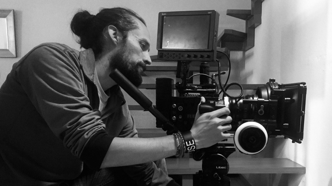 Cinematographer Alejandro Roa operating a professional RED cinema camera on set.