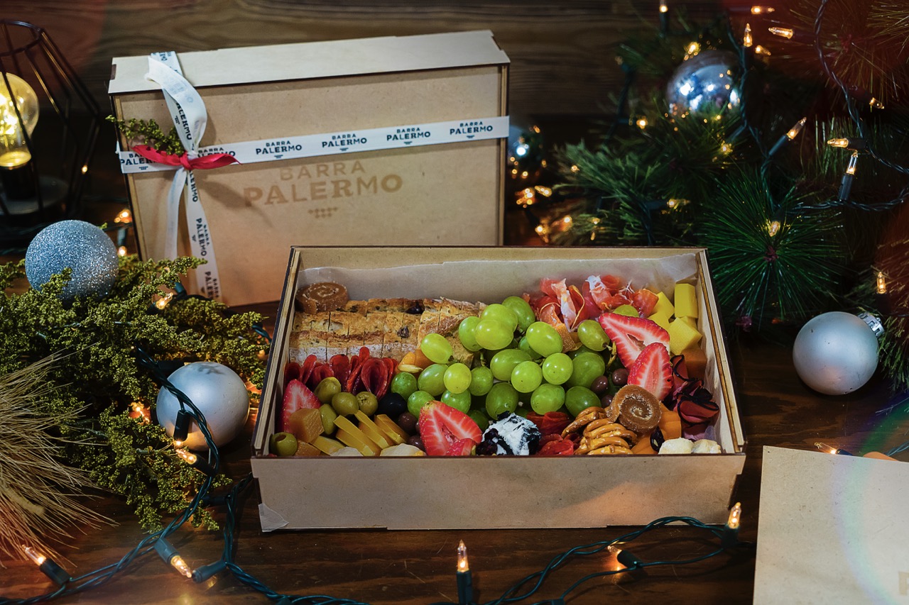 Christmas food tray with fruits, cheeses, cold cuts, and bread presented in wooden box in festive setting