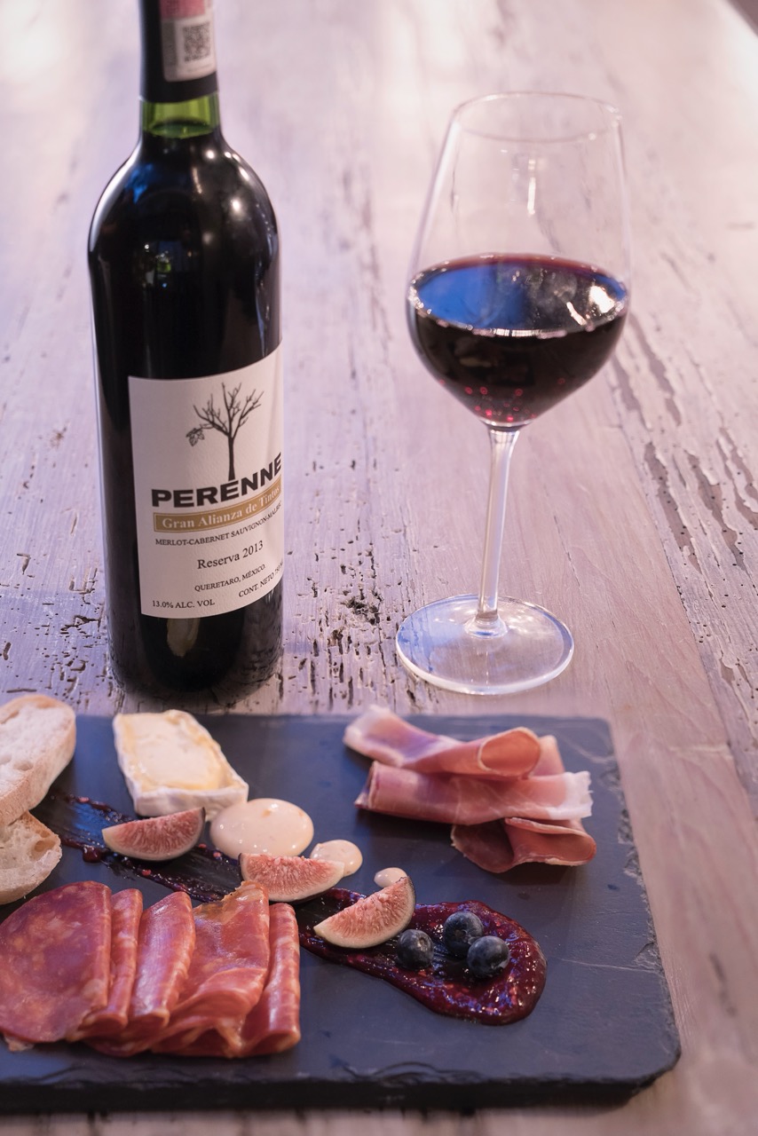 Wine glass filled with red wine next to plated food in a consumption setting