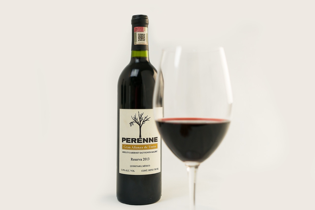 Wine bottle with glass showing Merlot, Cabernet, and Malbec blend on white background