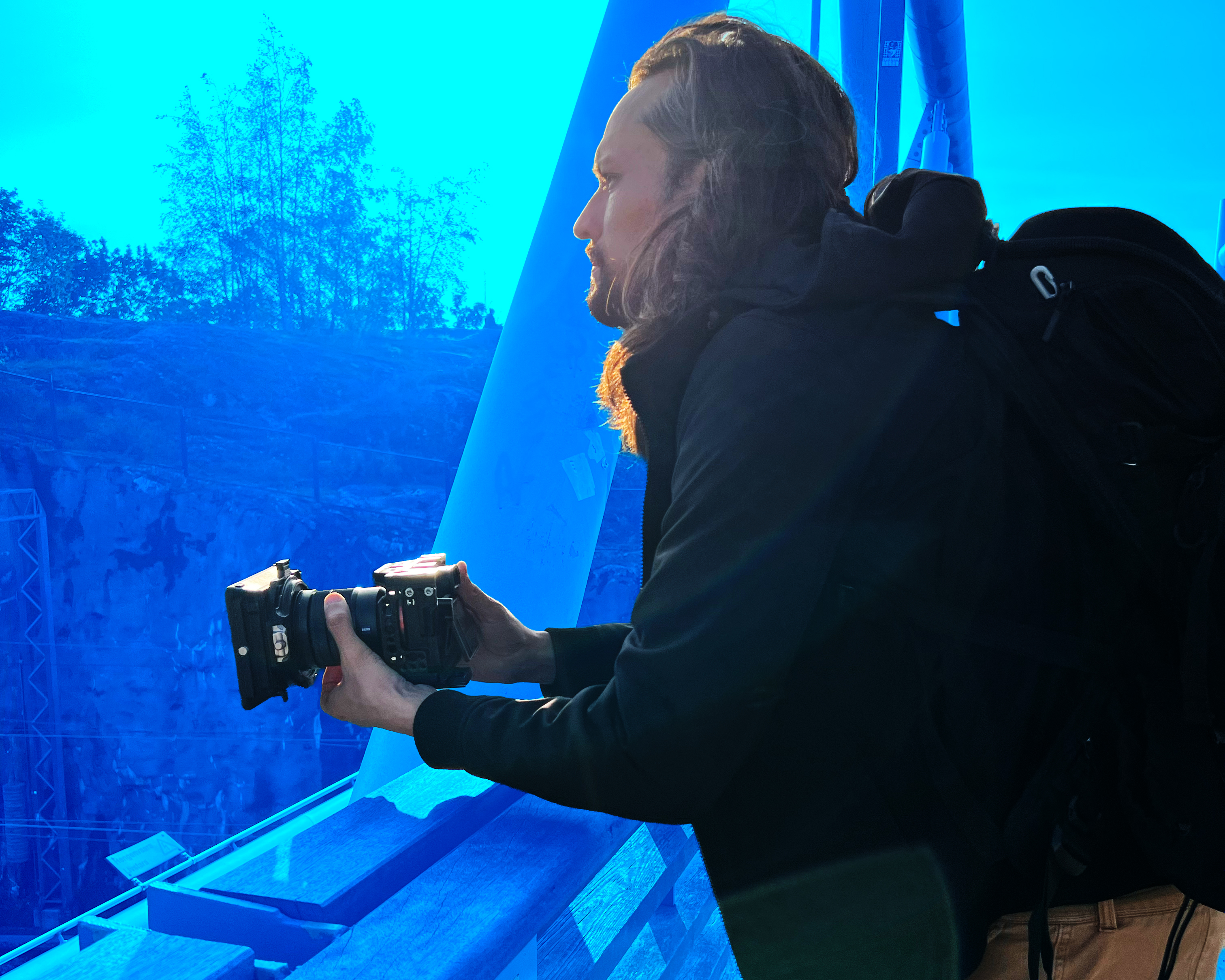Alejandro Roa Photographer holding a Sony camera equipped with a Tilta matte box, looking toward the horizon in a reflective moment.